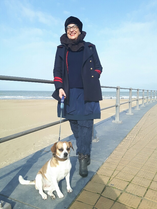 Älterwerden in Oostende: Die Betreiberin des Unruhewerks mit Hund auf Strandpromenade. Rentenbeginn, gelebter Eigensinn, Selbstständig älter werden, Rentenbeginn als Selbstständige