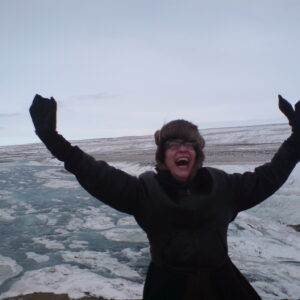 Island und Ich, Zeit und Älterwerden. Die Autorin grinsend mit erhobenen Armen vor Schneelandschaft
