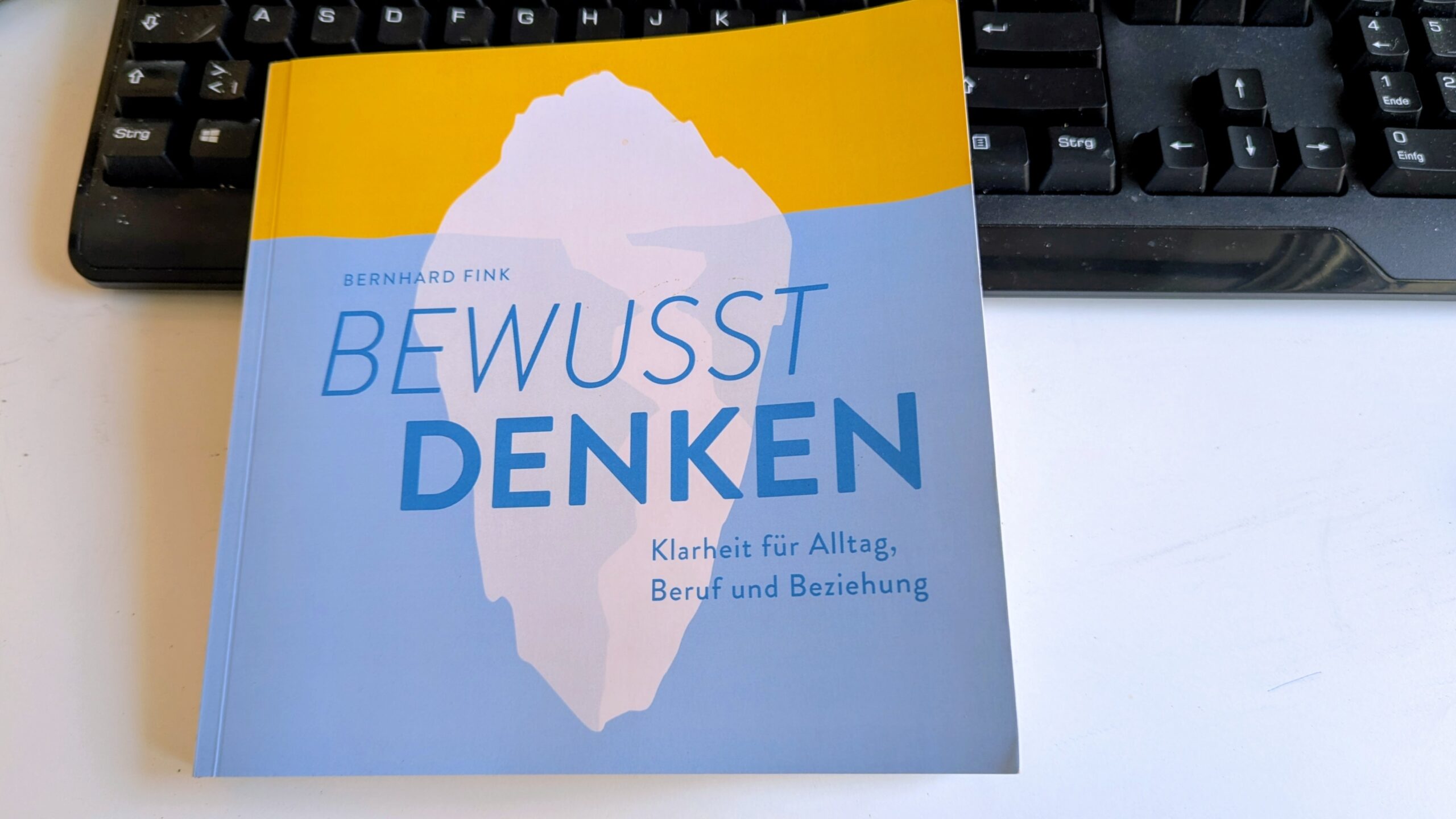 Das Buch "bewusst denken" von Bernhard Fink - Coverabbildung und im Hintergrund eine PC-Tastatur